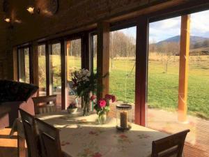 a dining room with a table and a large window at Medová chaloupka in Černá Voda