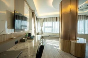 ein Wohnzimmer mit einer Couch und einigen Fenstern in der Unterkunft Enrich Grand Hotel in Bangkok