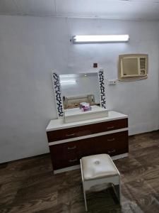 a dresser with a mirror and a stool in a room at غرفه مفروشه in Mogayra