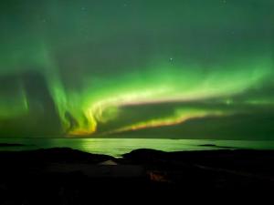 an aurora in the sky over a body of water at Drømmeplassen in Averoy +2 photos