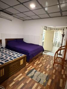 een slaapkamer met twee bedden en een houten vloer bij Waters meet surf villa in Weligama