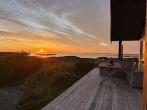 a sunset over the ocean with a table on a deck at Drømmeplassen in Averoy