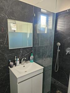 a bathroom with a sink and a shower with a mirror at Ocean view apart in Tel Aviv