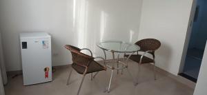 a glass table and chairs next to a small refrigerator at Hotel Villa do Sol in Colinas do Tocantins