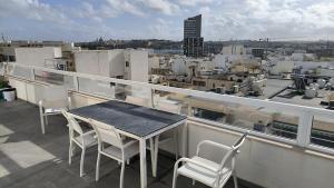 een tafel en stoelen op een balkon met uitzicht op een stad bij Large Terrace with Valletta Views in Il-Gżira