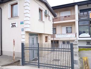 ein weißes Gebäude mit einem Zaun davor in der Unterkunft Apartmani Abbazia in Banja Luka