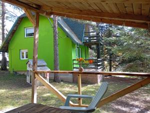 a green house with a chair in front of it at Petra Kuća Apartmani Studio Divčibare Петра Кућа Апартмани Студио Дивчибаре in Divčibare