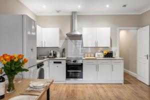 a kitchen with white cabinets and a wooden table at Spacious - Central - King Beds - Fast Wi-Fi in Brighton & Hove