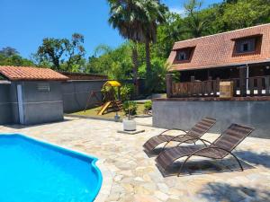 a patio with two chairs and a swimming pool at Recanto da Natureza in Matinhos