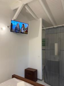 a tv on the wall of a bathroom with a shower at Bungalow cerise in Morne-à-lʼEau