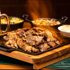 a plate of meat on a table with some food at Apartamentos Nadai 201 in Foz do Iguaçu