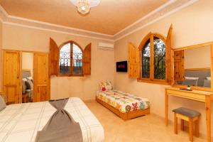 a bedroom with a bed and a desk and windows at Villa Korima in Marrakesh
