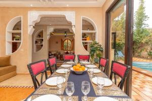 a dining room with a table and chairs and a pool at Villa Korima in Marrakesh