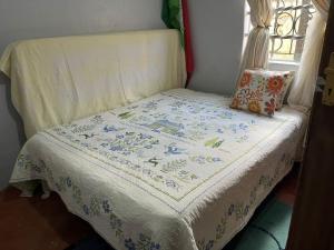 a bed with a quilt on it with a window at Lifeline Homes in Kiserian
