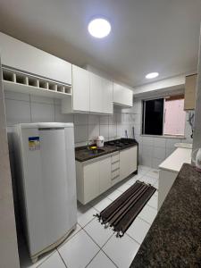 een keuken met witte kasten en een koelkast bij Ap 1km da praia Araçagi in São Luís