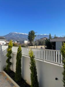 a white fence with trees and mountains in the background at Kremelo Hotel in Berat