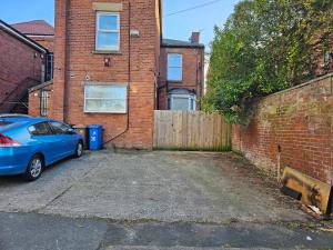 une voiture bleue garée devant un bâtiment en briques dans l'établissement Manchester Ashton Suites, à Ashton-under-Lyne