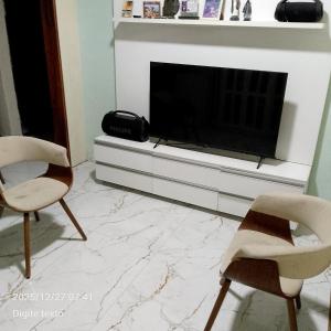 a living room with two chairs and a television at Aconchego particular in Guaramiranga