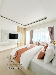 een slaapkamer met een groot bed en een tv aan de muur bij Lavani Living Hotel in Tjakranegara