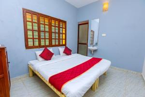 a bedroom with a large bed with red pillows at Greens Heritage Resort with Swimming Pool in Auroville
