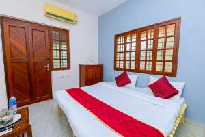 a bedroom with a large white bed with red pillows at Greens Heritage Resort with Swimming Pool in Auroville