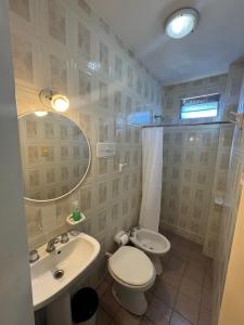 een badkamer met een toilet, een wastafel en een spiegel bij HColon in Colón +22 foto's