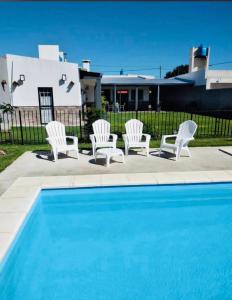 eine Gruppe weißer Stühle neben einem Pool in der Unterkunft Quinta Altos del Prado in San Nicolás de los Arroyos