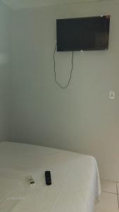 een tv aan een muur boven een bed bij Pousada praia avenida in Maceió