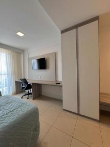 een slaapkamer met een bed en een bureau met een televisie bij Studio vista panorâmica completo in Macaé