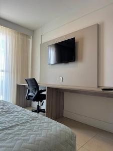 een hotelkamer met een bed, een stoel en een televisie bij Studio vista panorâmica completo in Macaé