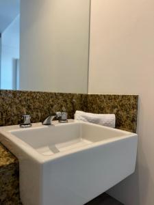 un lavandino bianco in un bagno con uno specchio di Studio vista panorâmica completo a Macaé