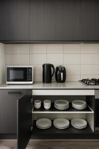 a kitchen with a microwave and plates on a shelf at Comfortable Home stay in Pimpama