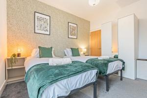 two beds in a room with green and white sheets at 3BR Sheffield Home - Contractor Friendly with WiFi in Sheffield +32 photos