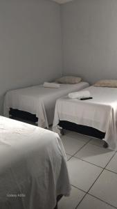 twee bedden in een kamer met witte muren bij Pousada praia avenida in Maceió