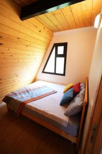 a bed in a wooden room with a window at La Madera Resort in Turbul