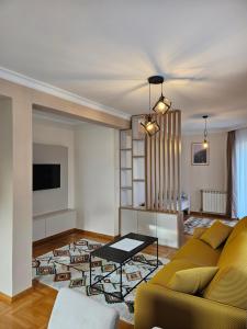 een woonkamer met een gele bank en een tv bij Velike Šume Apartment in Pale