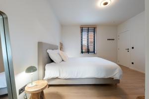 een witte slaapkamer met een groot bed en een raam bij Huys van Haeghe in Zoutleeuw