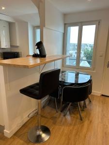een keuken met een bar met stoelen en een glazen tafel bij Le Naval - Confort Familial in Saint-Nazaire +10 foto's
