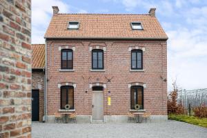 een rood bakstenen gebouw met een deur en twee banken bij Huys van Haeghe in Zoutleeuw