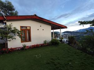 een klein wit huis met een groene tuin bij Ella Black Bridge View Cottage Sri Lanka in Ella