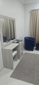 een kamer met een bureau met een spiegel en een blauwe stoel bij صدي للشقق المخدومة in Quai