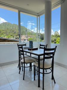 ein Esszimmer mit Tisch und Stühlen und Fenstern in der Unterkunft Quiet Haven Terrace with BBQ Hammock in Vilcabamba