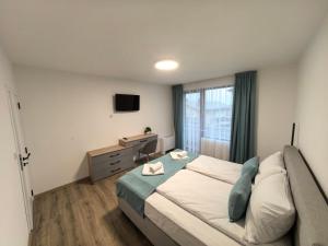 een slaapkamer met een groot bed en een televisie bij Карина - къща за гости in Ognyanovo