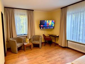 een kamer met 2 stoelen, een tafel en 2 ramen bij Boutique HOTEL am KRANICHSEE in Hahnenklee-Bockswiese