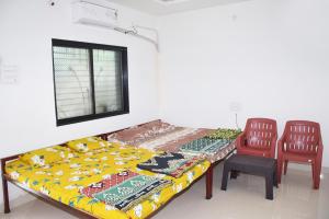 a bedroom with a bed and two chairs and a table at Daneshwari Bhakt Niwas in Akalkot