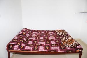 a bed with a blanket on top of it at Daneshwari Bhakt Niwas in Akalkot