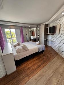 a bedroom with a large bed with a tv on the wall at Refúgio da Lagoa in Florianópolis