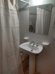 een badkamer met een wastafel en een spiegel bij Cabañas y Camping El Gringo in Quequén