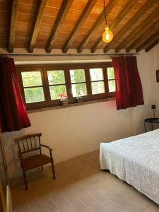 科尔托纳BORGO IN SAN ANGELO的一间卧室，里面有一张床、一把椅子和几扇窗户。