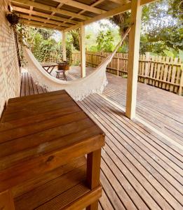 a wooden porch with a hammock and a table at Cabana Rosa na mata in Imbituba